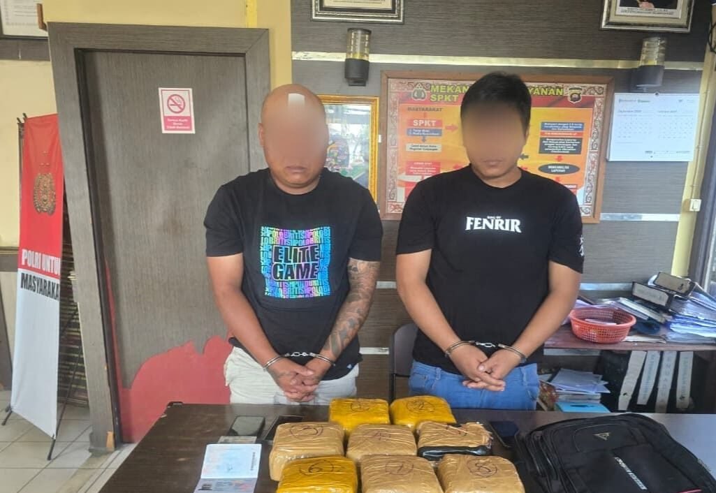 "Dua dari tiga tersangka sindikat narkoba internasional, yang merupakan warga negara Malaysia, berpose bersama barang bukti sabu 8 kg di Polsek Tayan Hulu. (Dok. Arya/Faktakalbar.id)"