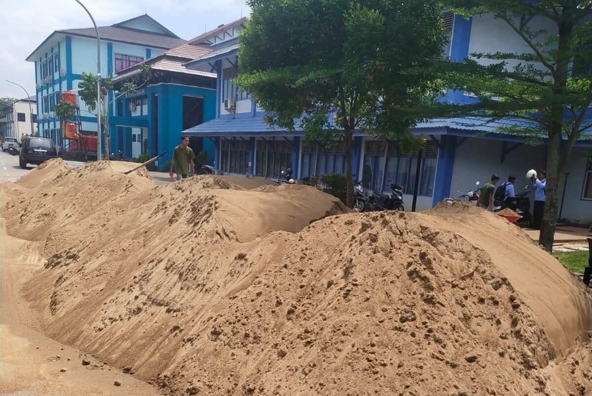 Tumpukan material dan pengerjaan fisik di lokasi proyek pembangunan infrastruktur yang terpantau berjalan tanpa dilengkapi papan informasi pelaksanaan kegiatan.