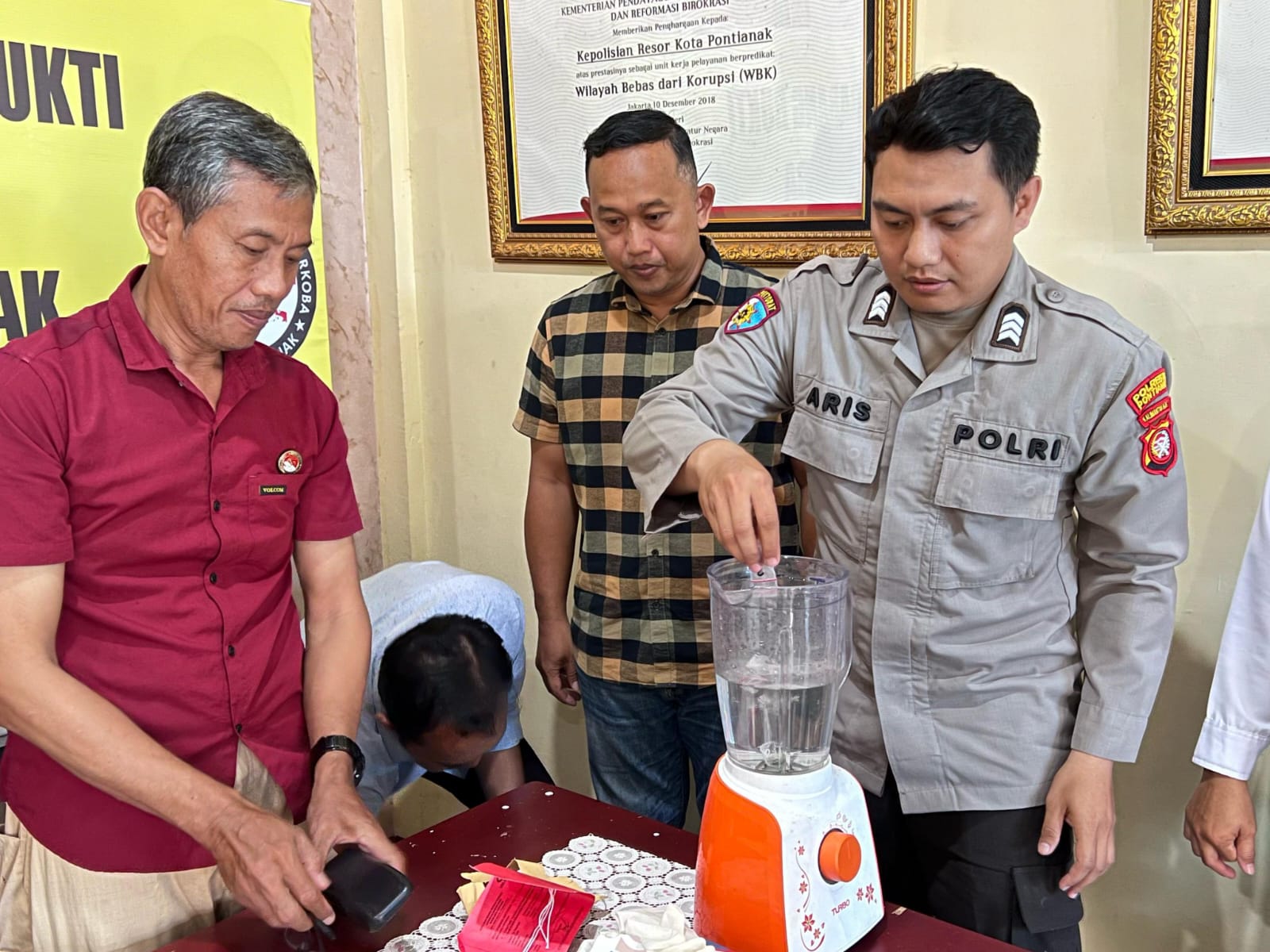 Seorang petugas Satresnarkoba Polresta Pontianak memasukkan barang bukti narkotika ke dalam blender saat proses pemusnahan, disaksikan oleh perwakilan kejaksaan dan pihak terkait, Kamis (6/3/2025). Foto (Dok. Polresta Kota Pontianak/Faktakalbar.id)