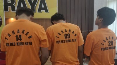 Polrest Kubu Raya amankan Tiga pria dengan baju tahanan oranye bertuliskan "Tahanan Polres Kubu Raya" berdiri membelakangi kamera dalam konferensi pers terkait kasus perdagangan orang.