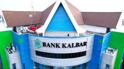 Gedung kantor pusat Bank Kalbar di Jalan Rahadi Usman, Pontianak, dengan desain modern berwarna biru, putih, dan hijau, serta atap berbentuk segitiga berwarna cokelat. Bangunan ini dikelilingi oleh area perkotaan dengan beberapa gedung dan vegetasi di sekitarnya, diambil dari sudut pandang udara.