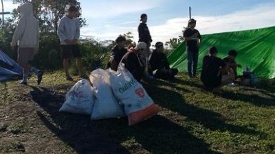 Sekelompok pendaki beristirahat di puncak Bukit Rentap, Sintang, dengan beberapa kantong sampah berisi plastik di sekitar mereka.