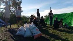 Sekelompok pendaki beristirahat di puncak Bukit Rentap, Sintang, dengan beberapa kantong sampah berisi plastik di sekitar mereka.