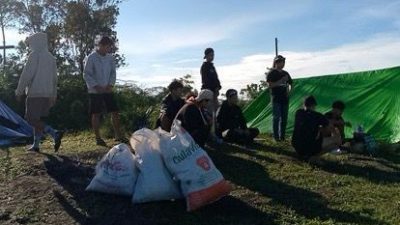 Sekelompok pendaki beristirahat di puncak Bukit Rentap, Sintang, dengan beberapa kantong sampah berisi plastik di sekitar mereka.