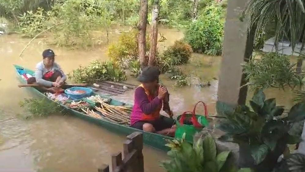 Dua warga berada di atas sampan saat banjir melanda Kapuas Hulu, Kalimantan Barat. Mereka mengangkut barang dagangan untuk berjualan di tengah genangan air.