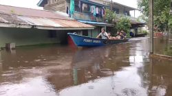 Sebuah perahu berisi beberapa warga melintasi jalan yang terendam banjir di Desa Wirayuda, Kecamatan Ketungau Tengah. Air hampir mencapai bagian bawah rumah panggung, sementara pakaian tergantung di lantai dua rumah.