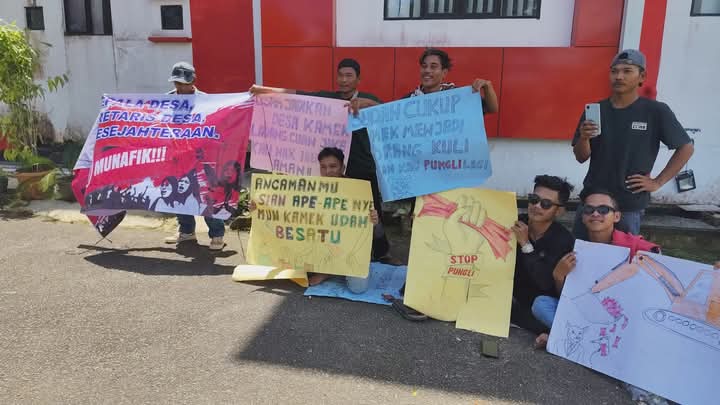 Beberapa warga memegang poster yang berisi bentuk kekecewaan mereka terhadap Kepala Desa Pelimpaan saat aksi di Kantor Inspektorat Kabupaten Sambas, Senin (19/5/2025). (Dok. Ist)