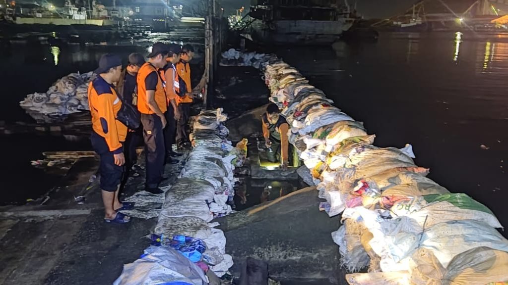 Upaya BPBD Provinsi Jawa Tengah bersama BPBD Kota Semarang menutup 24 meter area penghalang gelombang pasang air laut yang jebol dan menyebabkan banjir permukiman warga di kawasan Pelabuhan Tanjung Mas, Kota Semarang, Provinsi Jawa Tengah pada Jumat (23/5). Sumber foto : BPBD Kota Semarang.