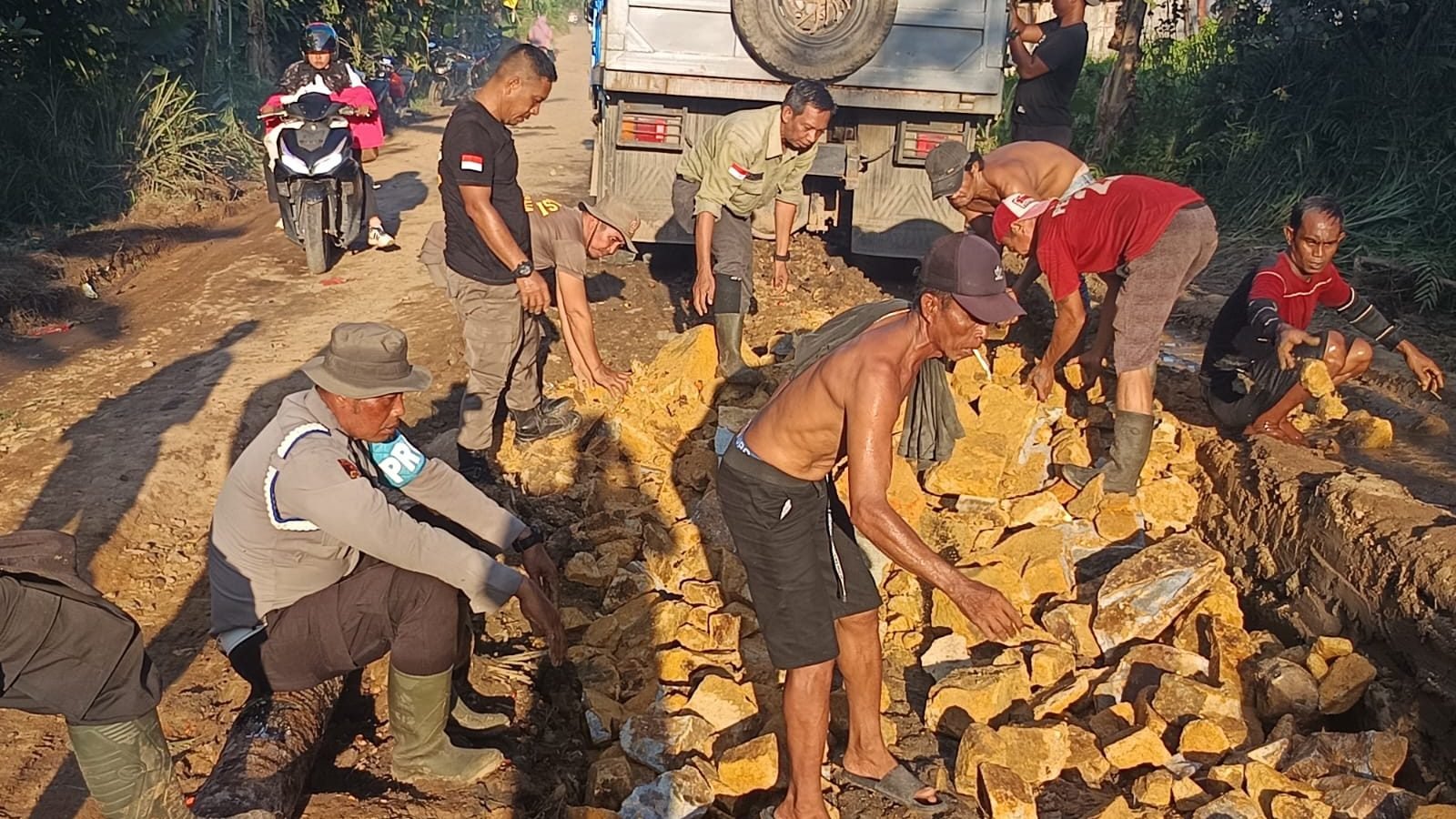 Anggota Polres Kayong Utara dan warga bahu membahu menimbun jalan berlubang di jalur mudik antar-kecamatan, Rabu (5/6/2025). Foto: HO/Faktakalbar.id