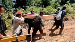 Warga Dusun Tokot bergotong royong menandu seorang ibu yang mengalami pendarahan pasca melahirkan, melintasi jalan rusak di pedalaman Bengkayang. (Dok. Ist)