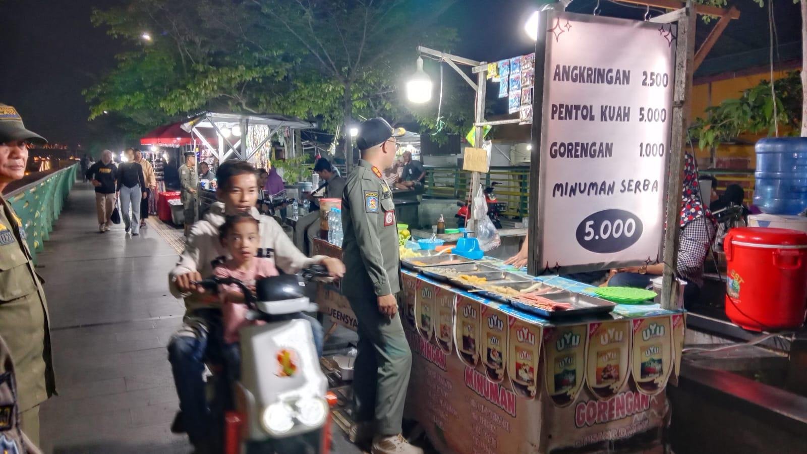Petugas Satpol PP Kota Pontianak saat memberikan imbauan persuasif kepada salah seorang pedagang di kawasan waterfront agar turut serta menjaga kebersihan dan tidak membuang sampah ke Sungai Kapuas, Minggu (20/7/2025) malam. Foto: HO/Faktakalbar.id