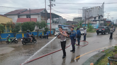 Petugas Satlantas dan Damkar Sekadau membersihkan tumpahan solar di Jalan Merdeka, Sekadau Hilir. (Dok. Polres Sekadau)