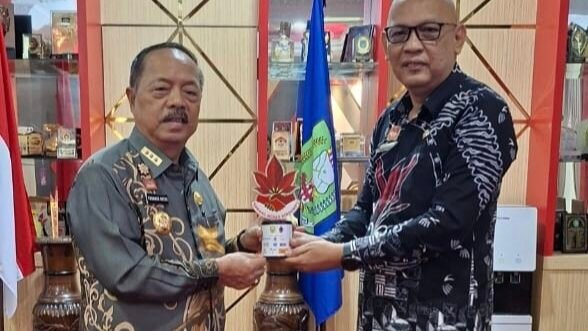 Plt. Kepala Bapperida Sanggau, Shopiar Juliansyah (kiri), saat menyerahkan laporan kegiatan dan plakat Sabang Merah Berdompu kepada Bupati Sanggau di ruang kerjanya, Kamis (21/8/2025).