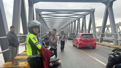 Personel Lantas Polsek Pontianak Timur membersihkan tumpahan solar yang membahayakan pengendara di atas Jembatan Landak, Sabtu (9/8/2025).