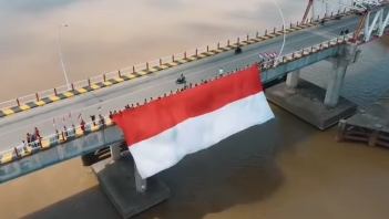 Relawan Rumah Zakat bersama anggota Pramuka SMAN 01 Tayan Hilir membentangkan bendera Merah Putih raksasa di atas Jembatan Tayan, Kabupaten Sanggau, dalam rangka peringatan HUT RI ke-80.
