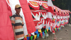 Seorang pedagang bendera Merah Putih menanti pembeli di tengah lesunya penjualan menjelang perayaan HUT Kemerdekaan RI ke-80 akibat persaingan dengan toko online.