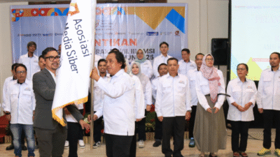 Wakil Ketua Umum AMSI Pusat, Upi Asmaradhana (kiri), menyerahkan bendera pataka kepada Ketua AMSI Kalbar, Muhlis Suhaeri, sebagai simbol pengukuhan pengurus baru periode 2025–2029. (Dok. Faktakalbar.id)