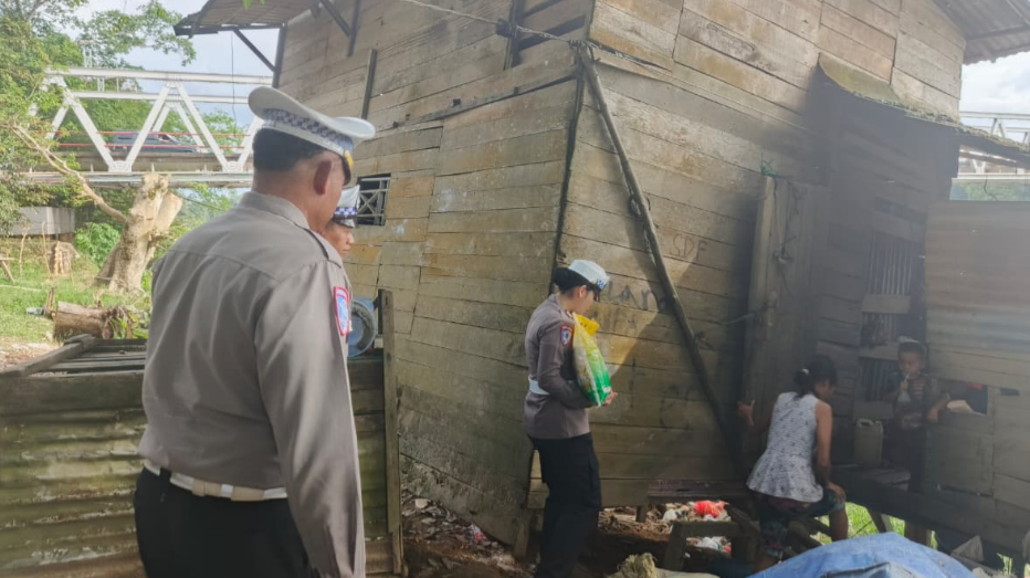 Petugas Satlantas Polres Melawi sedang menyerahkan paket sembako kepada seorang warga di tepi sungai. (Dok. HO/Faktakalbar.id)