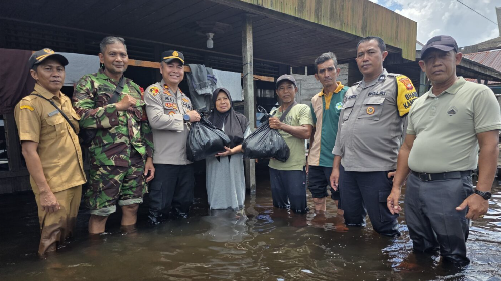 Kapolsek Manis Mata, Meinardus, saat menyerahkan bantuan sosial kepada seorang warga yang terdampak banjir Sungai Jelai. (Dok. HO/Faktakalbar.id)