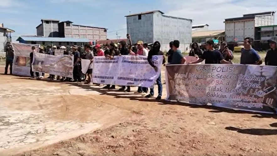 Warga Air Upas membentangkan spanduk saat aksi damai di depan kantor Kecamatan, menuntut aparat berantas peredaran narkoba di wilayah mereka.