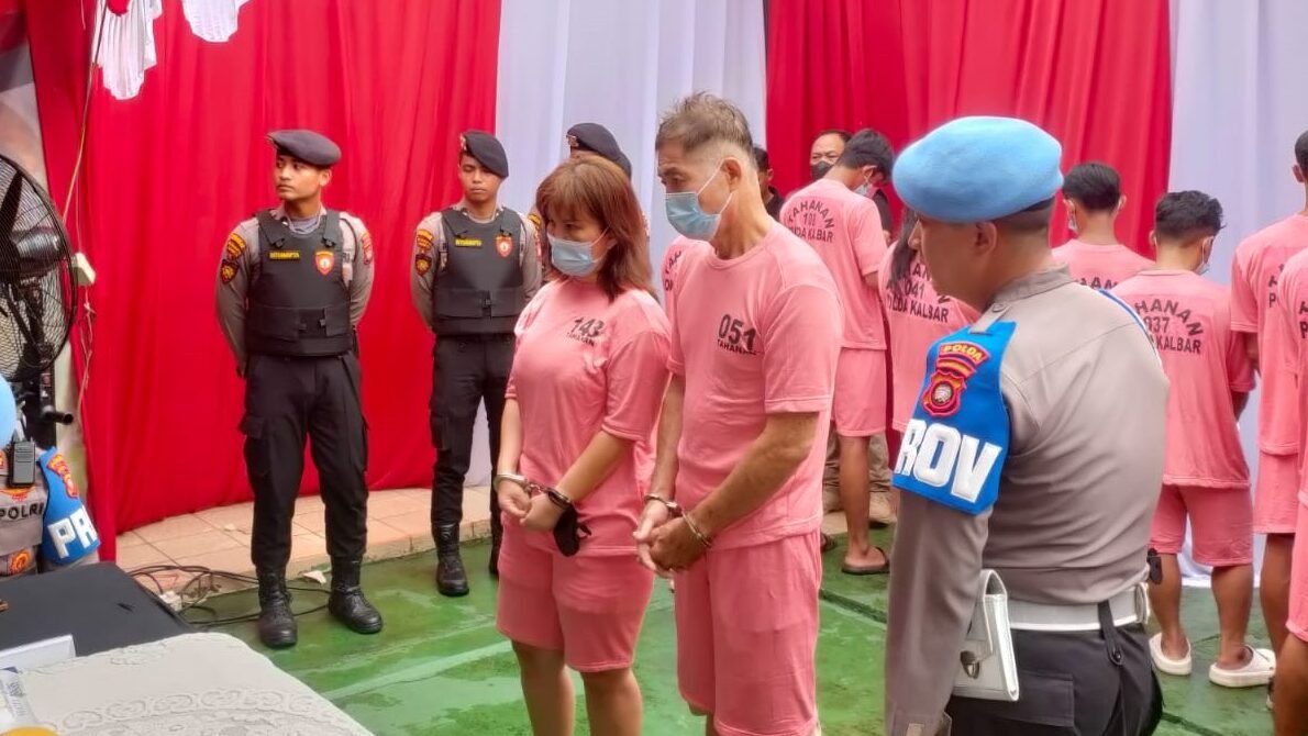 Dua tersangka YTH dan YMH, pasangan suami istri asal Malaysia, berpose di hadapan media setelah ditangkap oleh pihak kepolisian.