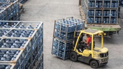 Ilustrasi - Pekerja mengangkut air minum dalam kemasan (AMDK) galon dengan alat pemberat. (Dok. Ist)