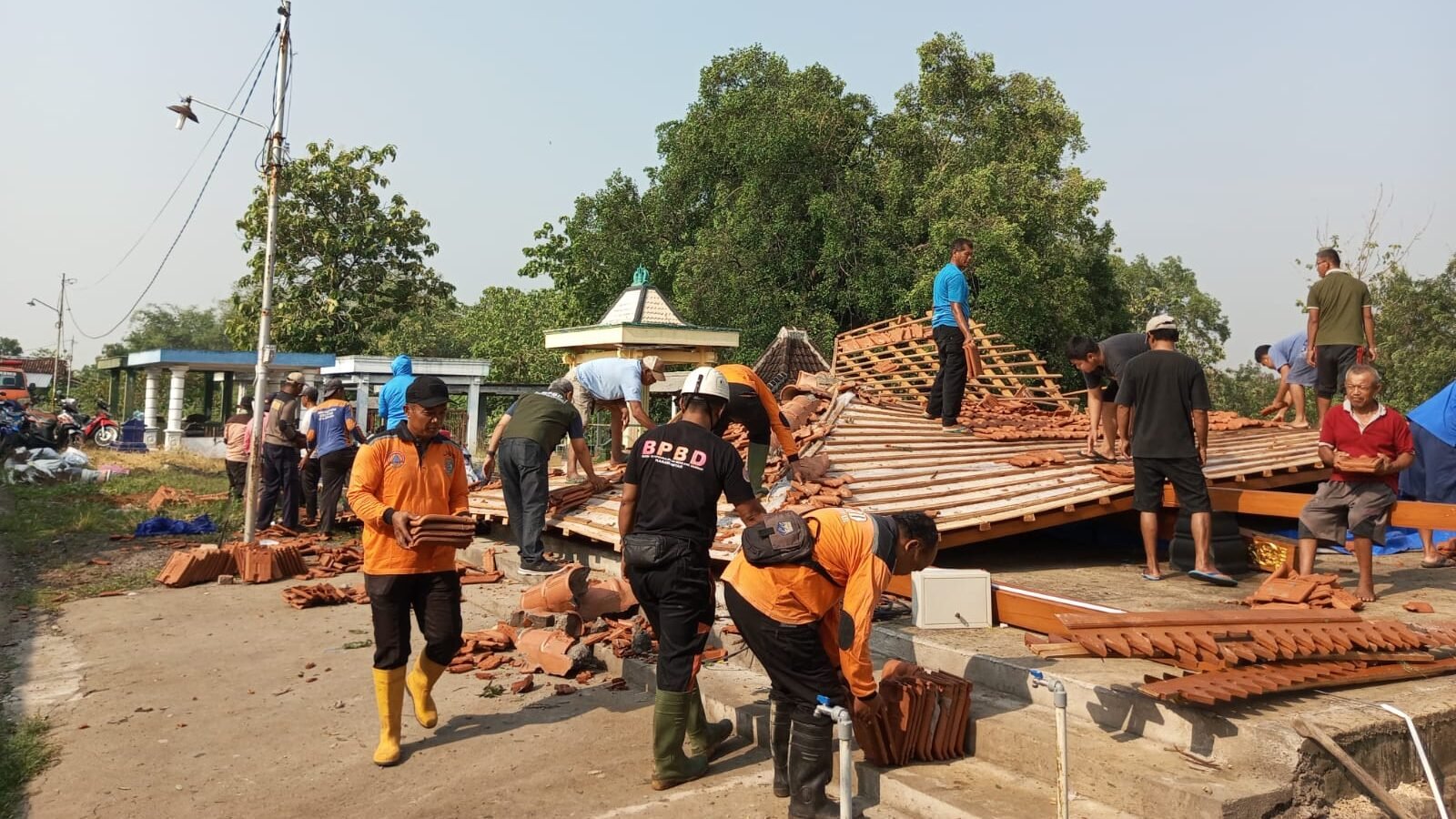 Petugas membantu warga melakukan pembersihan rumah warga yang rusak akibat angin kencang dan pohon tumbang di Kecamatan Gondangrejo, Kabupaten Karanganyar, Jawa Tengah pada Sabtu (18/10). Foto: BPBD Kab. Karanganyar
