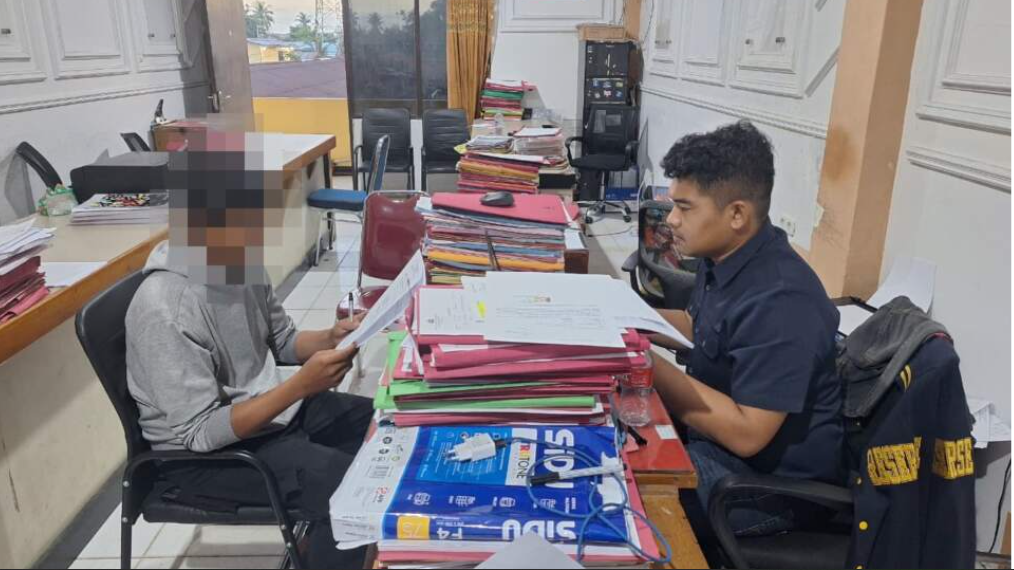 Seorang pria yang berprofesi sebagai kurir duduk di kursi kantor polisi, terlihat lemas dan memegangi kepalanya setelah sandiwara begal yang ia buat untuk menutupi kejahatannya terungkap. (Dok. Polres Ketapang)