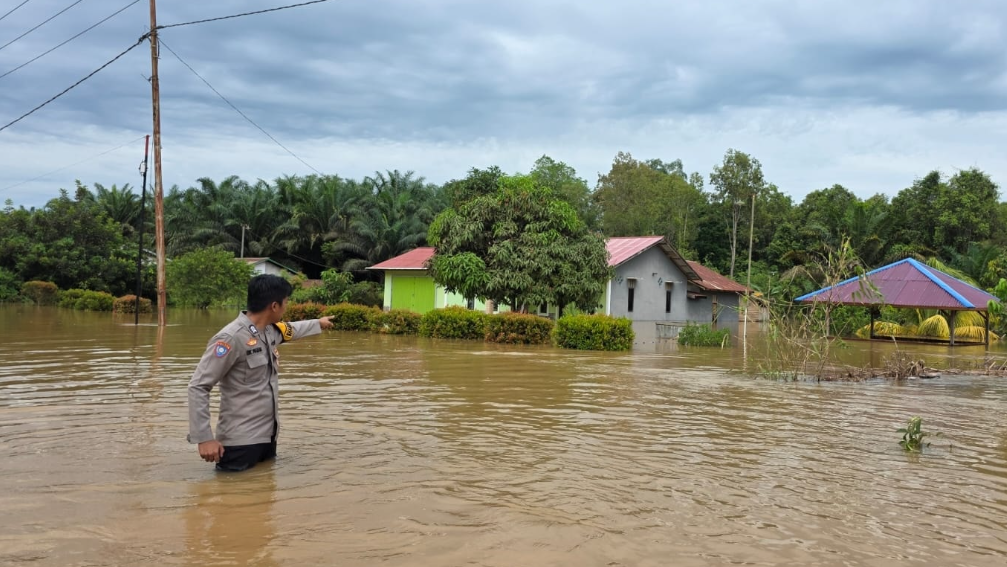 Bhabinkamtibmas Polsek Marau meninjau kondisi rumah warga yang terdampak banjir di Desa Karya, Kecamatan Marau. (Dok. Polsek Marau)