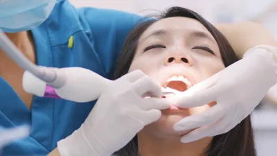 Ilustrasi: Dokter gigi sedang melakukan prosedur scaling atau pembersihan karang gigi pada pasien di fasilitas kesehatan.