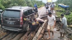 Kapolsek Simpang Hilir, AKP Dede Saepul Mikdar, bersama personel Bhabinkamtibmas saat bergotong royong mengevakuasi kendaraan warga yang terperosok di jembatan rusak, Kamis (20/11/2025).