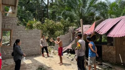 Personel Polsek Parindu bersama warga saat meninjau lokasi rumah yang rusak parah akibat tertimpa pohon tumbang di Dusun Pulau Mpoh, Desa Gunam, Kecamatan Parindu, Jumat (21/11/2025).