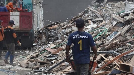 "Sejumlah pekerja yang mengenakan seragam partai biru terlihat di lokasi pembongkaran rumah Ahmad Sahroni di Tanjung Priok yang hancur pasca penjarahan."
