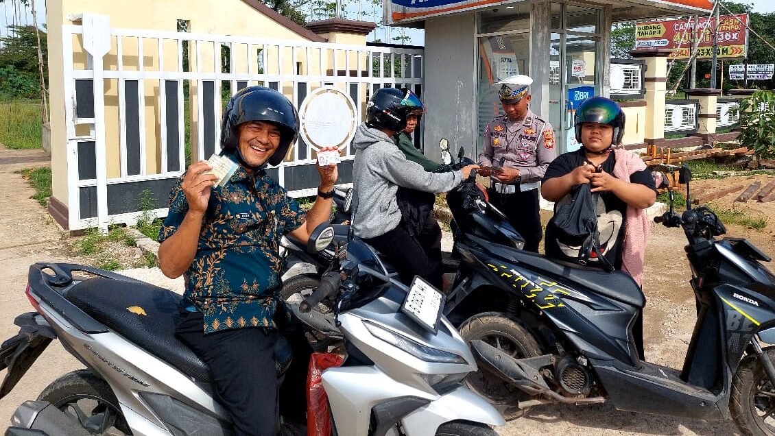 Seorang pengendara motor dengan senyum sumringah menunjukkan kelengkapan surat kendaraannya kepada petugas Polres Kubu Raya saat Operasi Zebra Kapuas 2025, Kamis (27/11/2025).
