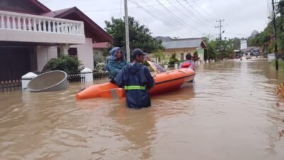 Petugas BPBD Kota Solok saat melakukan evakuasi warga menggunakan perahu karet di tengah pemukiman yang terendam banjir akibat luapan Sungai Batang Lembang, Kamis (27/11/2025).