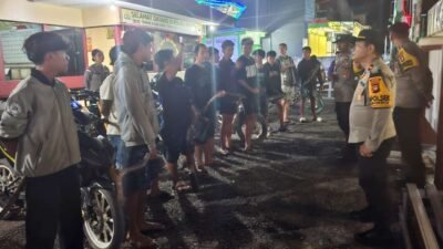 Petugas gabungan dari Polsek Parindu, Koramil, dan aparat desa saat mengamankan pengendara sepeda motor yang menggunakan knalpot brong dalam razia di Pasar Bodok, Jumat (14/11/2025) malam.