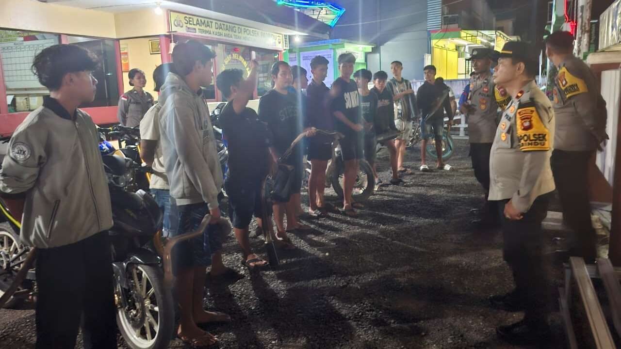 Petugas gabungan dari Polsek Parindu, Koramil, dan aparat desa saat mengamankan pengendara sepeda motor yang menggunakan knalpot brong dalam razia di Pasar Bodok, Jumat (14/11/2025) malam.