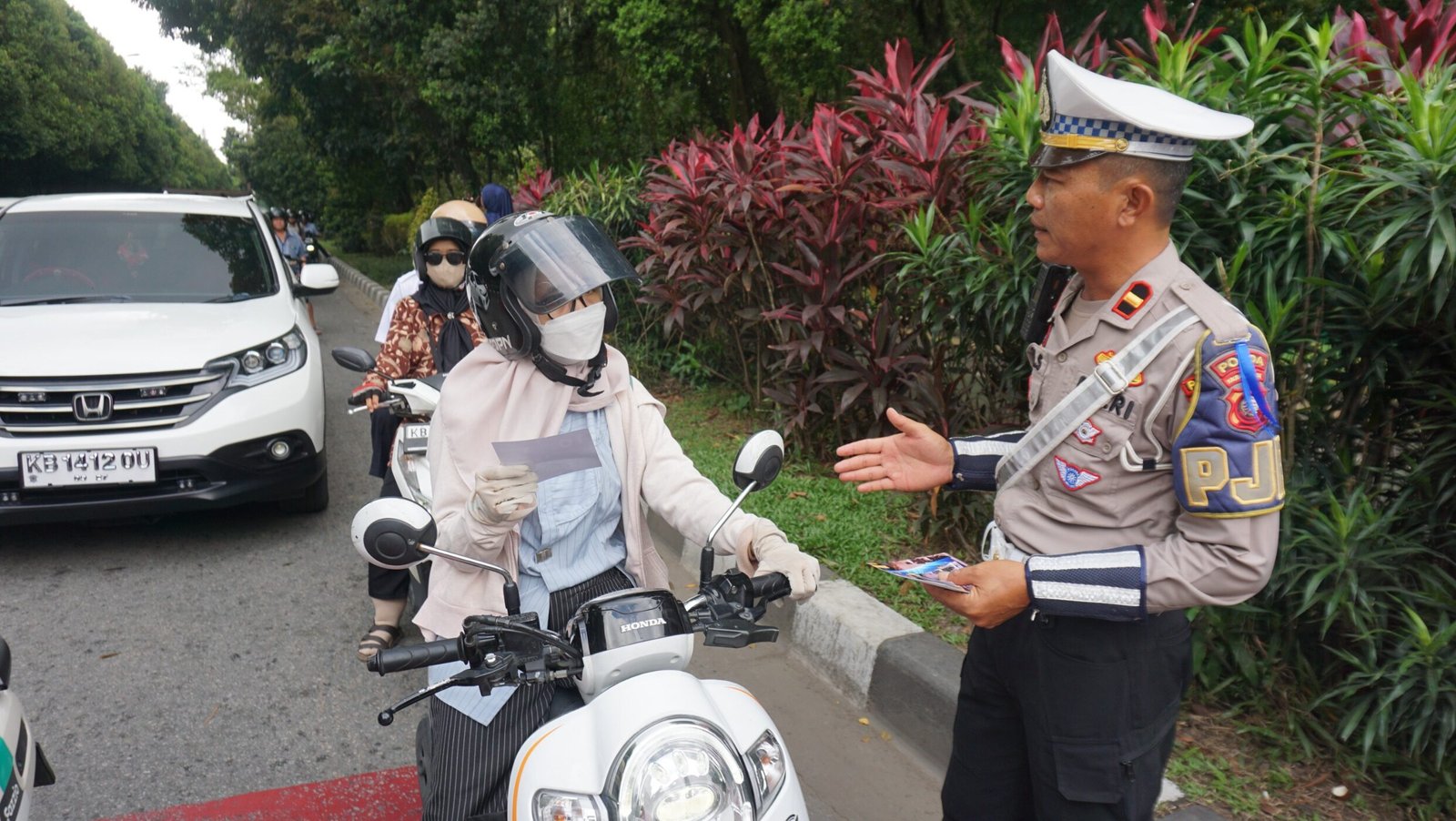 Personel Ditlantas Polda Kalbar memberikan brosur imbauan keselamatan kepada pengendara motor di Bundaran Untan, Pontianak, dalam rangkaian Operasi Zebra Kapuas 2025, Rabu (20/11/2025).