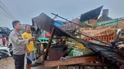 Personel Polres Landak bersama warga saat bergotong royong membersihkan puing-puing lapak yang roboh akibat diterjang angin kencang di kawasan Jembatan Baru Ngabang, Kamis (20/11/2025).