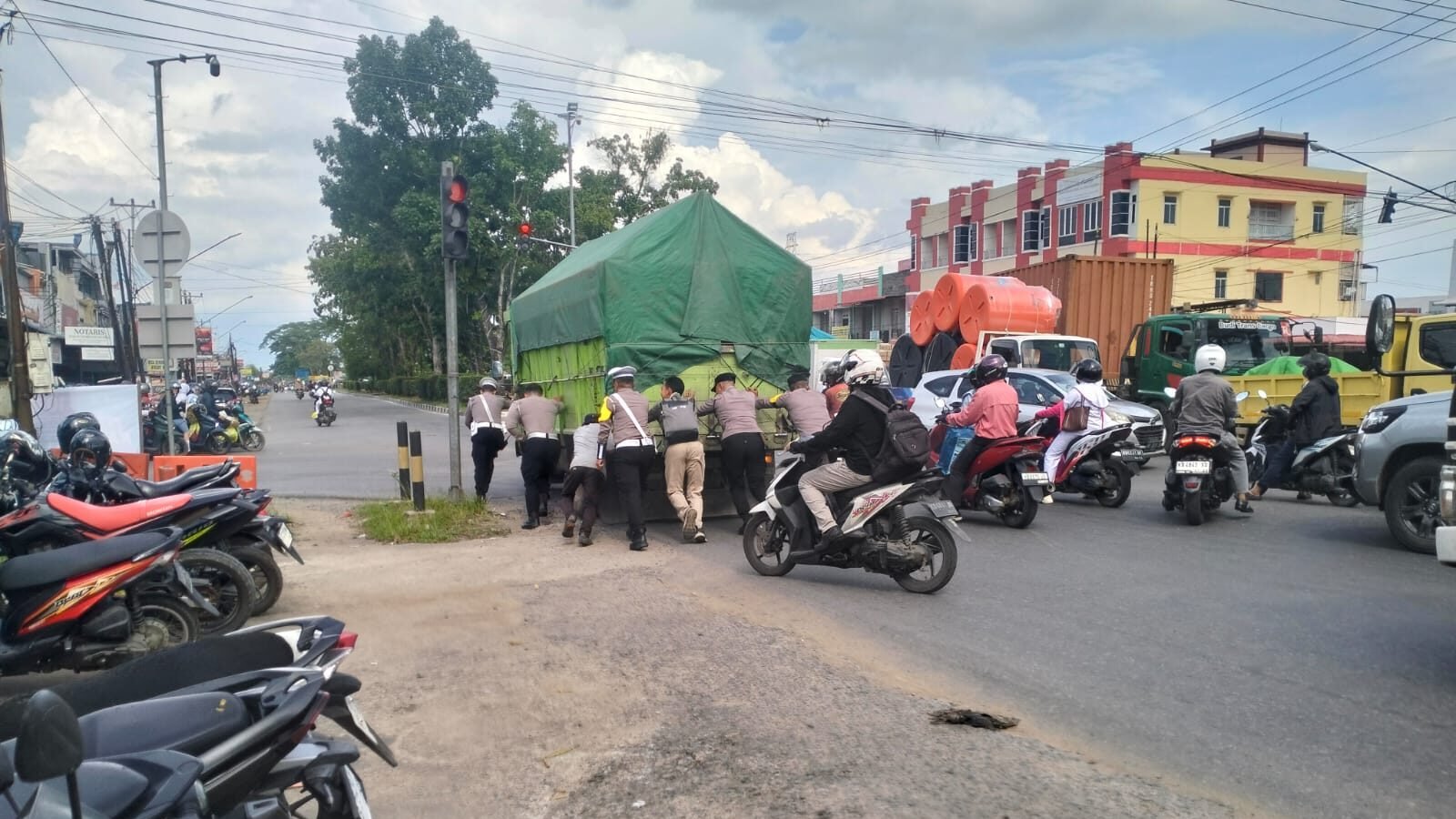 Personel Satlantas Polres Kubu Raya saat membantu mendorong truk yang mengalami kerusakan mesin di tengah Simpang Empat Desa Kapur, Sabtu (22/11/2025).