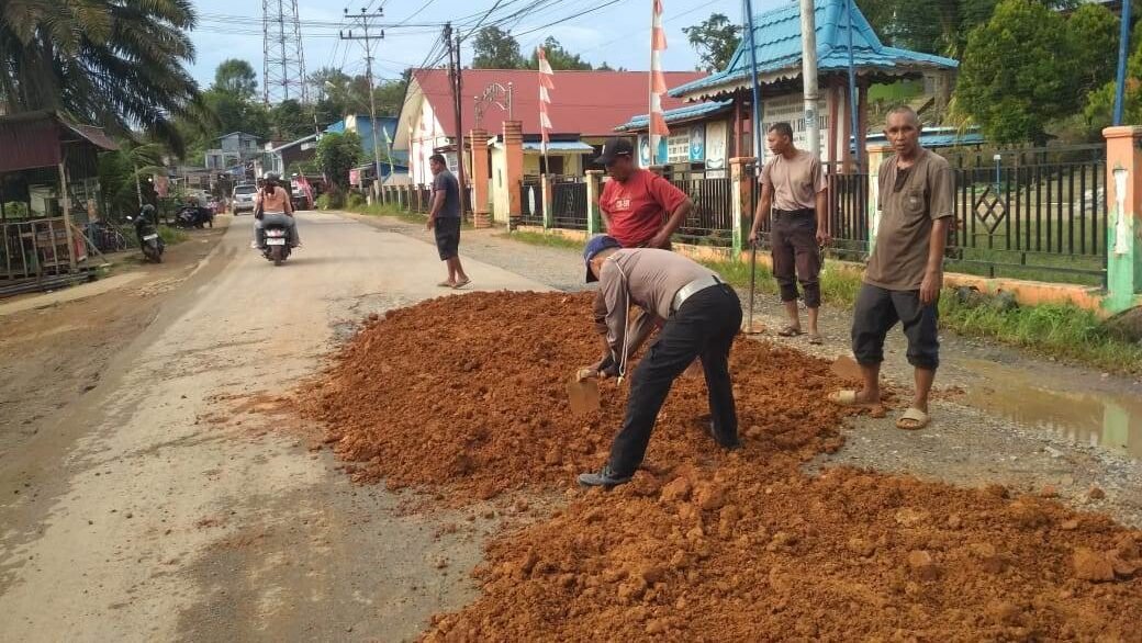 Anggota Polsek Tayan Hilir bersama warga saat melakukan kerja bakti menambal jalan berlubang di Jalan Pembangunan, Desa Kawat, Senin (17/11/2025).