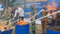 Petugas Bea Cukai Sintete saat melakukan proses pemusnahan barang bukti rokok ilegal dan barang kena cukai lainnya dengan cara dibakar di halaman kantor KPPBC Sintete, Selasa (25/11/2025).