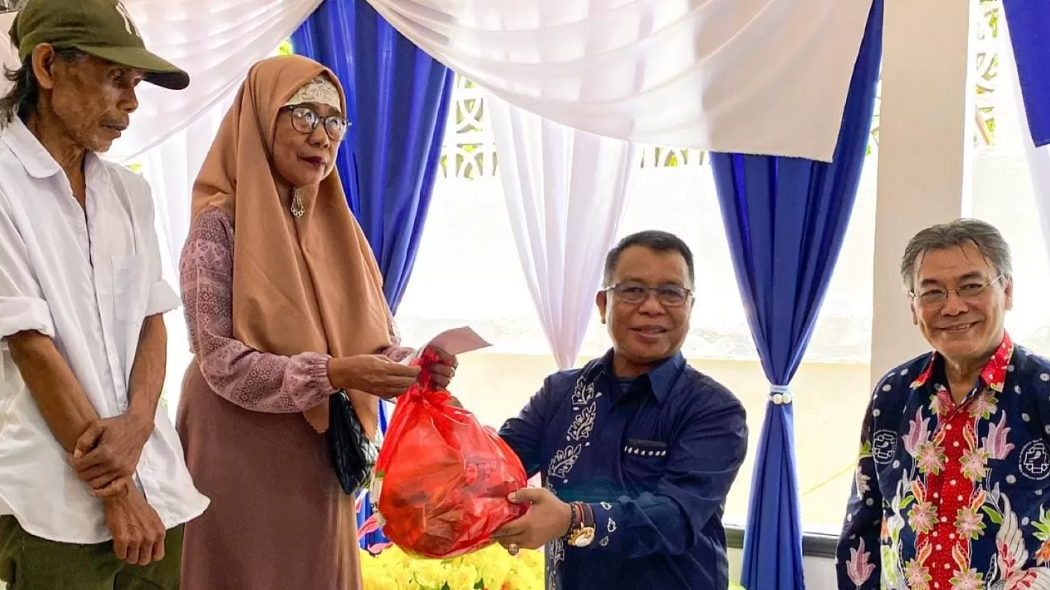 Staf Ahli Bupati Sintang, Helmi (tengah, baju biru), secara simbolis menyerahkan paket bantuan BAZNAS kepada seorang warga penerima manfaat didampingi pengurus. (Dok. HO/faktakalbar.id)