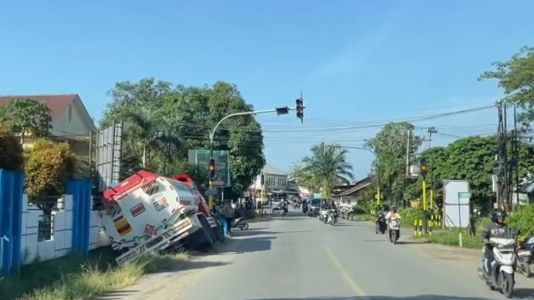 Sebuah mobil tangki berwarna merah putih terperosok miring ke dalam parit di Jalan YC Oevang Oeray, Sintang, dan bersandar di pagar kantor. (Dok. Ist)