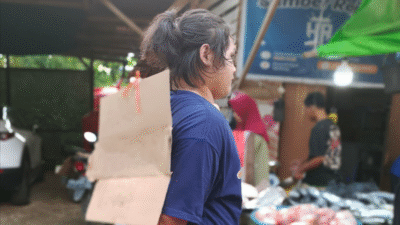 Seorang perempuan yang diduga pelaku pencurian ikan diamankan di Pasar Ngabang, Landak, dengan latar belakang lapak ikan. (Dok. Ist)