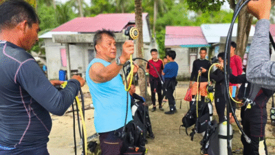 Sejumlah peserta, termasuk seorang pria berbaju biru, sedang antusias memeriksa dan mempersiapkan peralatan selam dalam pelatihan yang digelar DKP Kalbar di Desa Pelapis, Kepulauan Karimata. (Dok. HO/Faktakalbar.id)