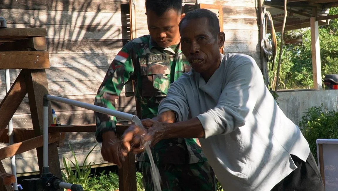 Seorang warga sedang menggunakan sumur bor air bersih di Desa Ratu Sepudak, Galing.