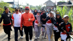 Bupati Kubu Raya Sujiwo mengenakan jaket oranye memberikan acungan jempol saat mengikuti jalan sehat bersama para guru di Sungai Kakap. (Dok. HO/Faktakalbar.id)