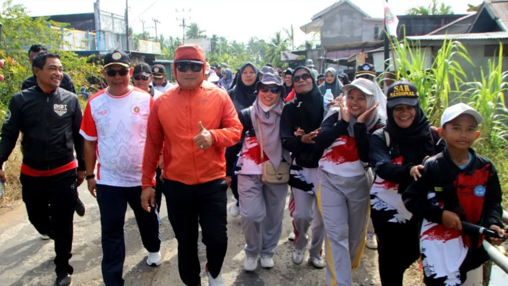 Bupati Kubu Raya Sujiwo mengenakan jaket oranye memberikan acungan jempol saat mengikuti jalan sehat bersama para guru di Sungai Kakap. (Dok. HO/Faktakalbar.id)