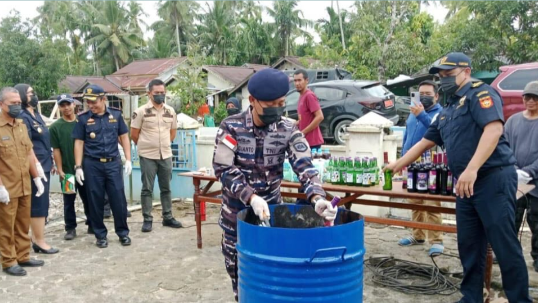 Personel TNI AL dan petugas Bea Cukai Sintete menuangkan minuman keras ilegal ke dalam drum saat pemusnahan barang bukti di Sambas. (Dok. HO/Faktakalbar.id)